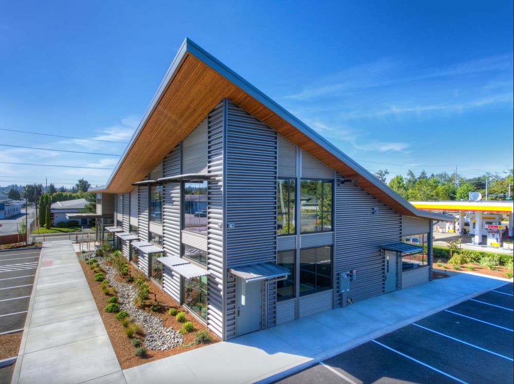 Modern commercial building with a sloped roof, large windows, and landscaped parking area.