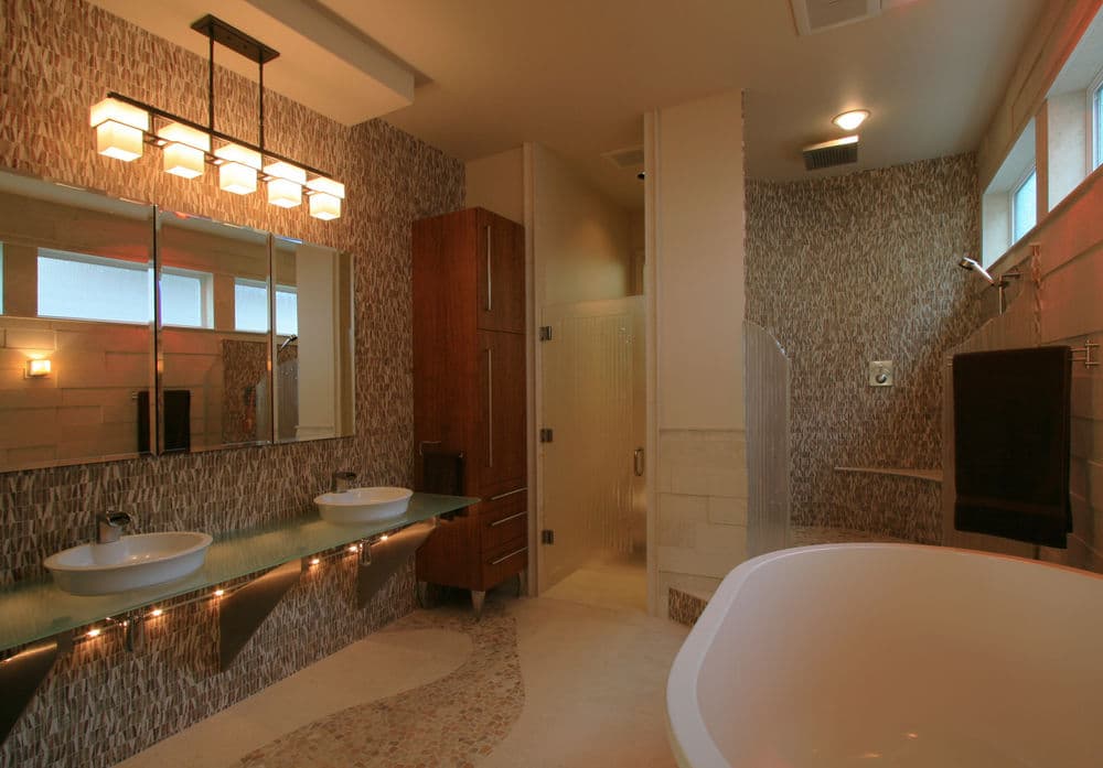 Modern bathroom featuring dual sinks, sleek cabinetry, and a glass shower enclosure.