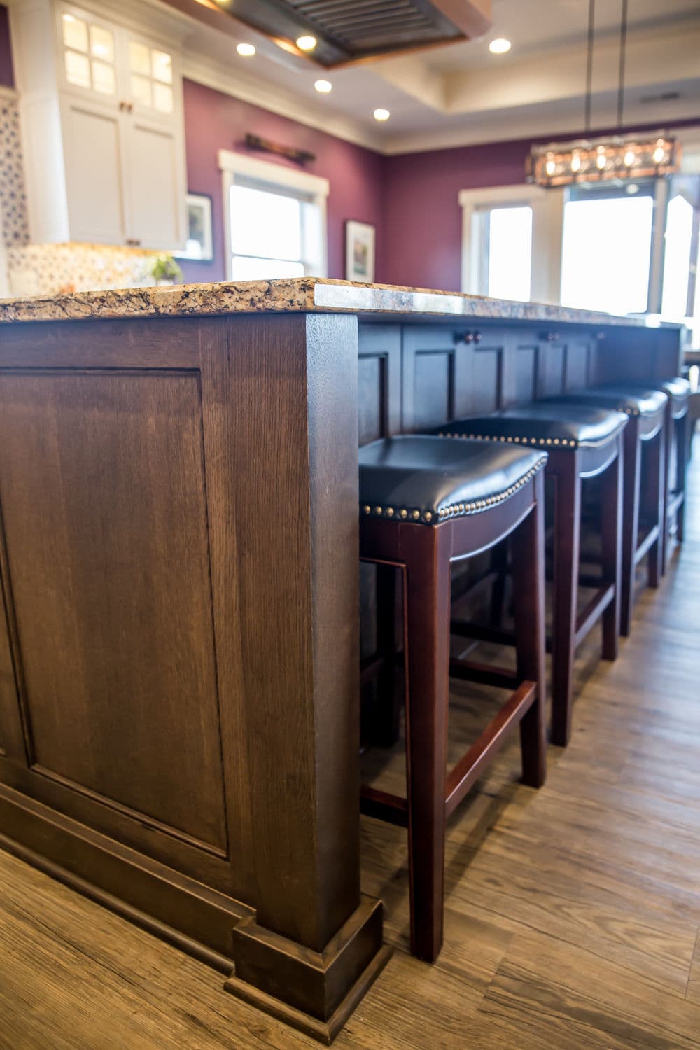 Modern kitchen bar with dark wood cabinetry and stylish leather stools. Elegant interior design details.