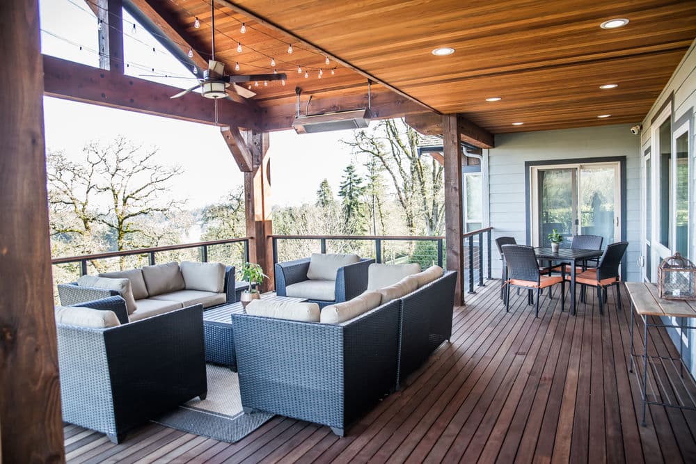 Cozy outdoor seating area with wicker furniture on a wooden deck surrounded by trees.