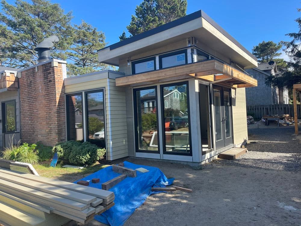 Modern cottage exterior with large windows, wooden accents, and gravel landscaping.