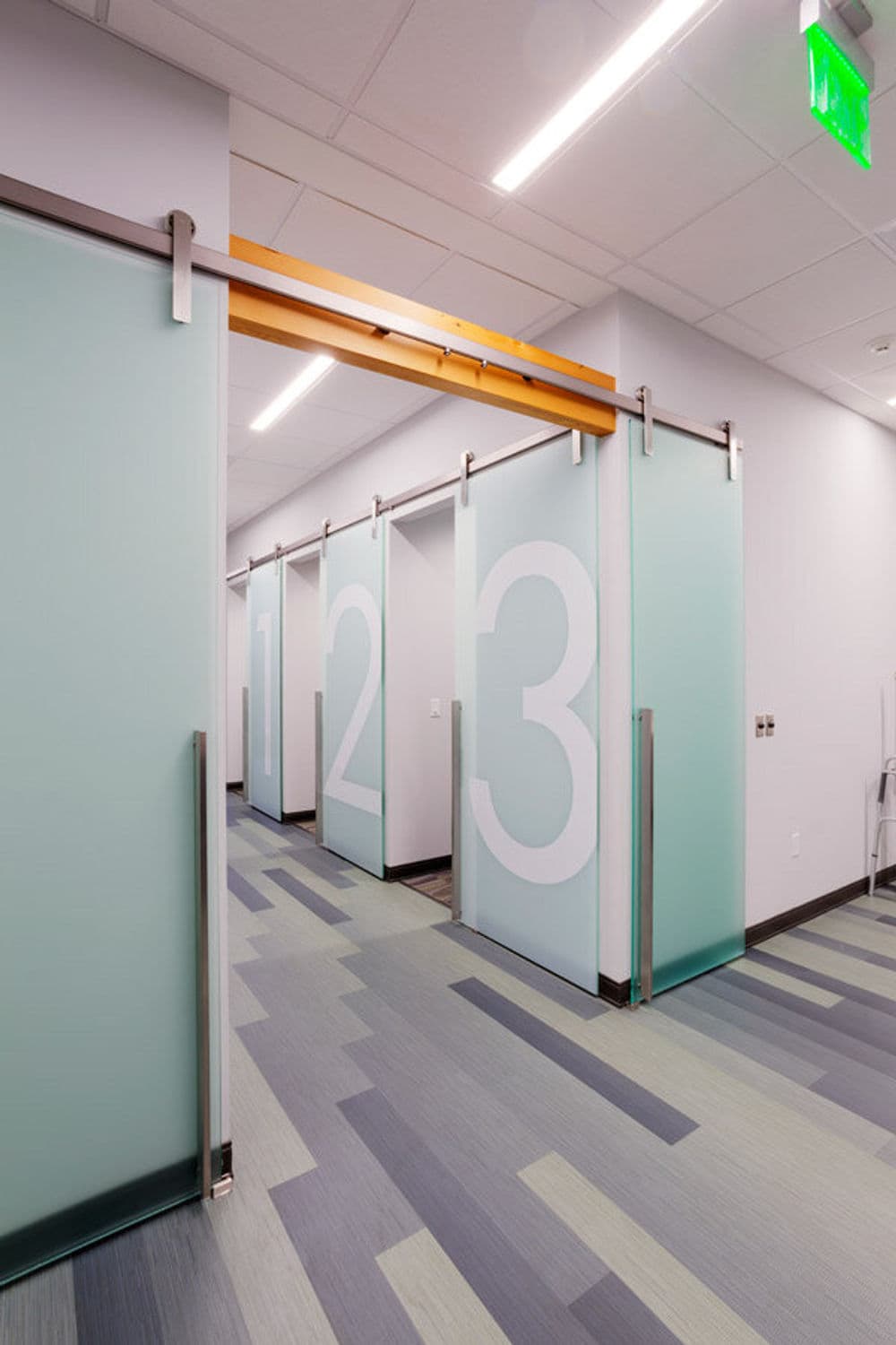 Modern office hallway with sliding glass doors numbered 1, 2, and 3 on frosted glass panels.