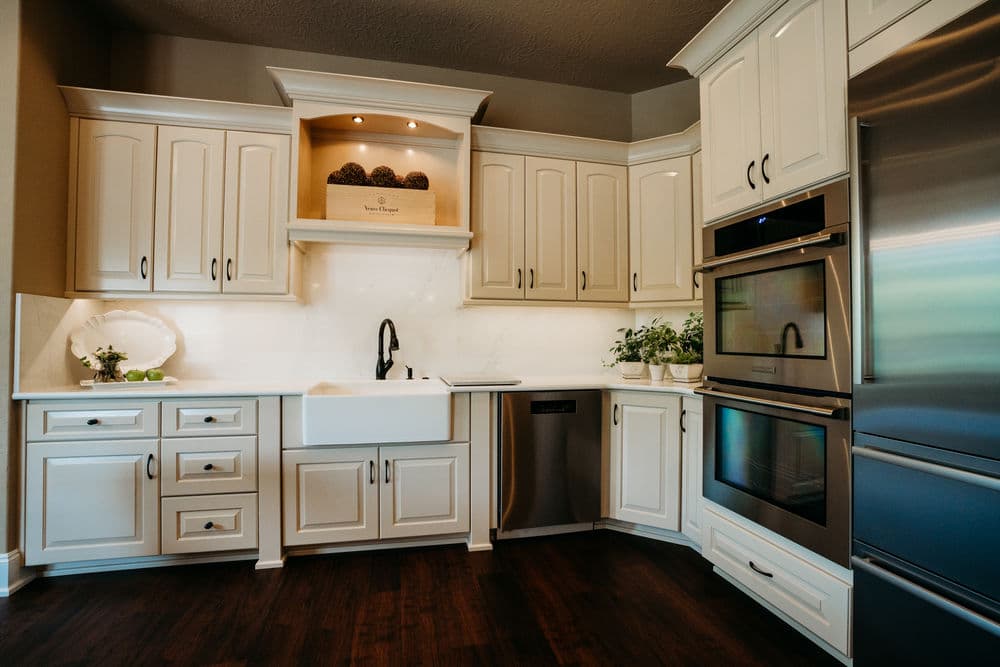 Modern kitchen with white cabinetry, farmhouse sink, stainless steel appliances, and dark hardwood flooring.
