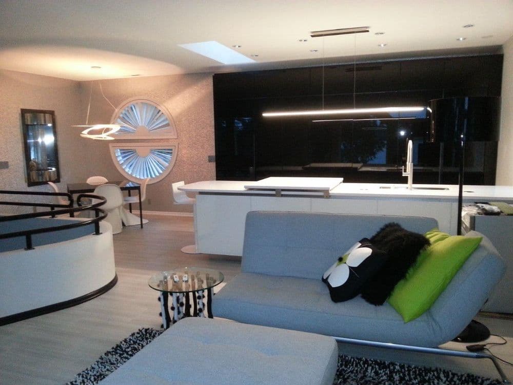 Modern minimalist living room featuring sleek furniture, a stylish light fixture, and unique decor.