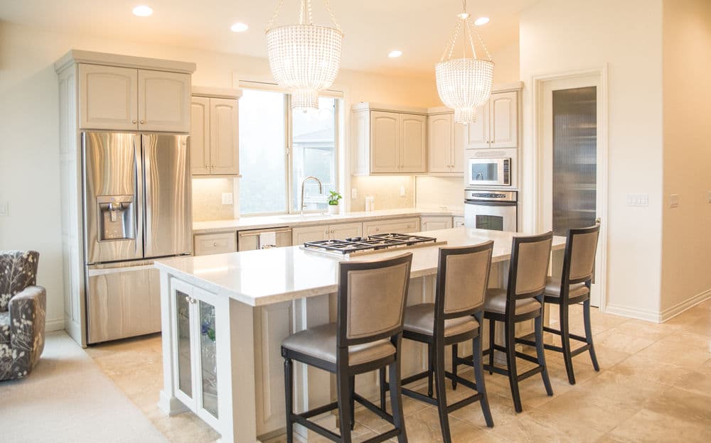 Modern kitchen with granite island, stainless steel appliances, and elegant pendant lighting.